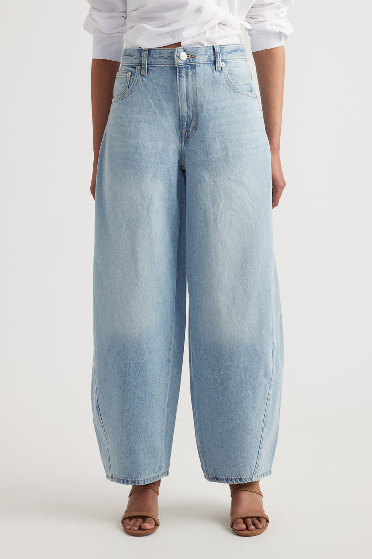Light blue wide-leg denim jeans with mid-rise waist, button and zip closure, styled with brown open-toe heels