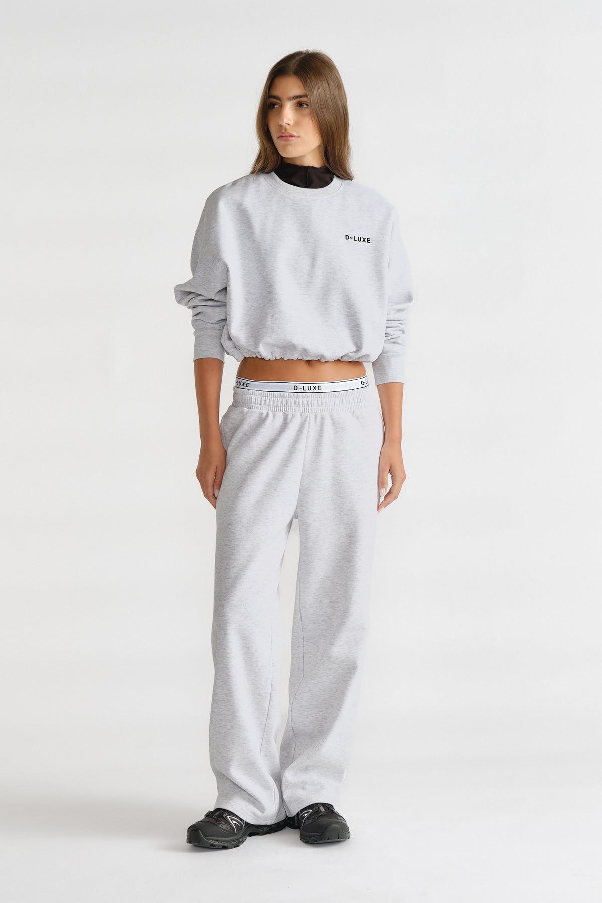 Woman wearing a grey D-Luxe Logo Crop Sweat with matching pants and black layered top, styled for casual comfort.