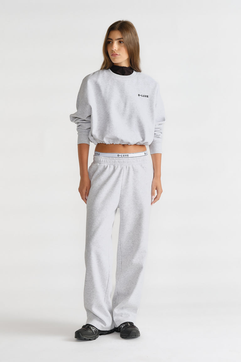 Woman wearing a grey D-Luxe Logo Crop Sweat with matching pants and black layered top, styled for casual comfort.
