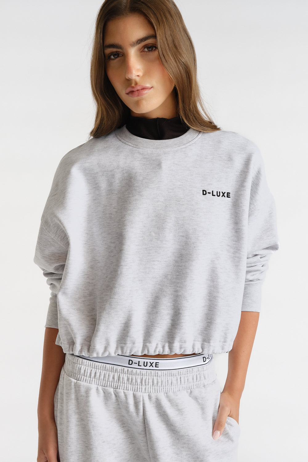 Woman wearing light grey D-Luxe Logo Crop Sweat with relaxed fit and subtle branding, styled casual and effortlessly chic.