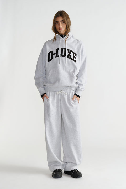 Woman wearing light grey hoodie with black lettering and matching wide-leg sweatpants with black sneakers