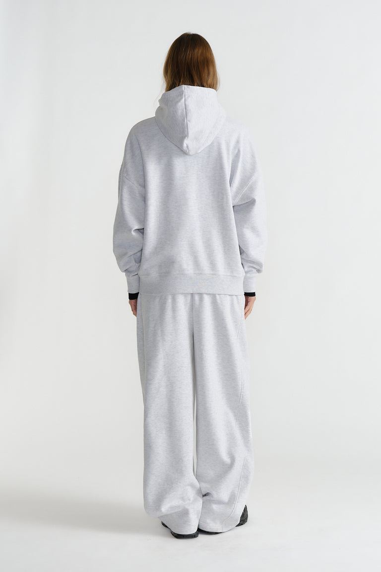Rear view of a model wearing a relaxed light grey hoodie and matching wide-leg pants in casual style