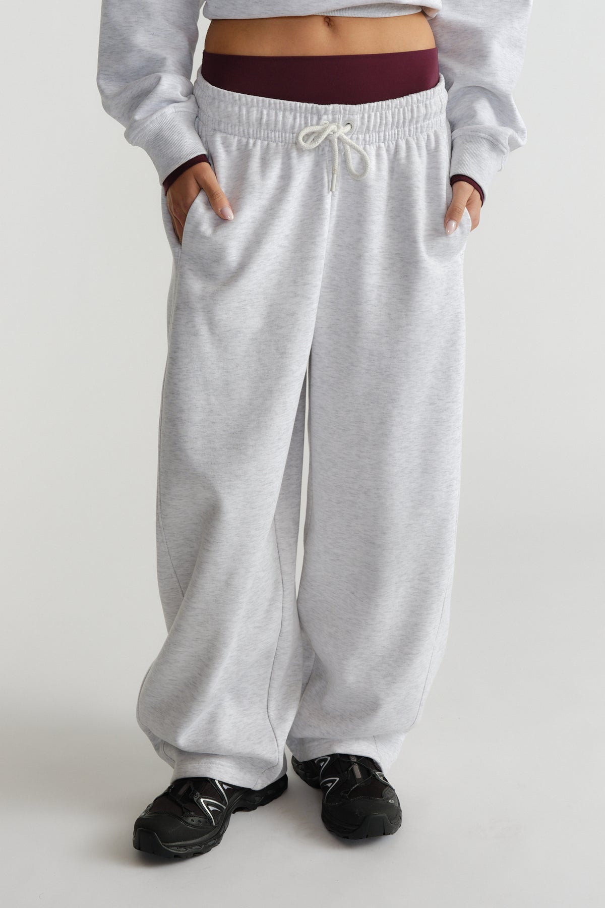 Woman wearing relaxed light grey barrel track pants with elastic waistband and casual black sneakers