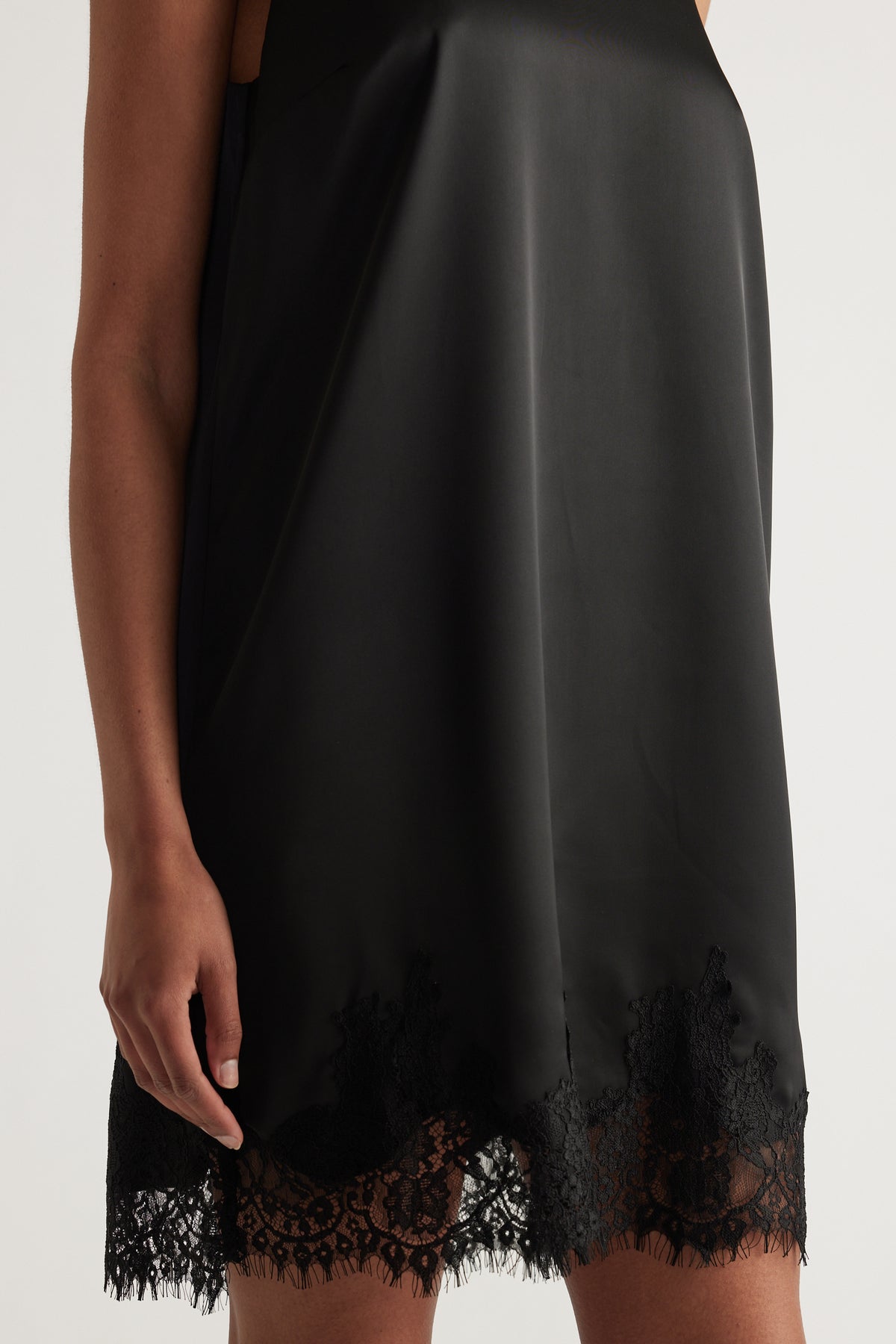 Black sleeveless mini dress with a flowing shift fit and scalloped lace trim hem