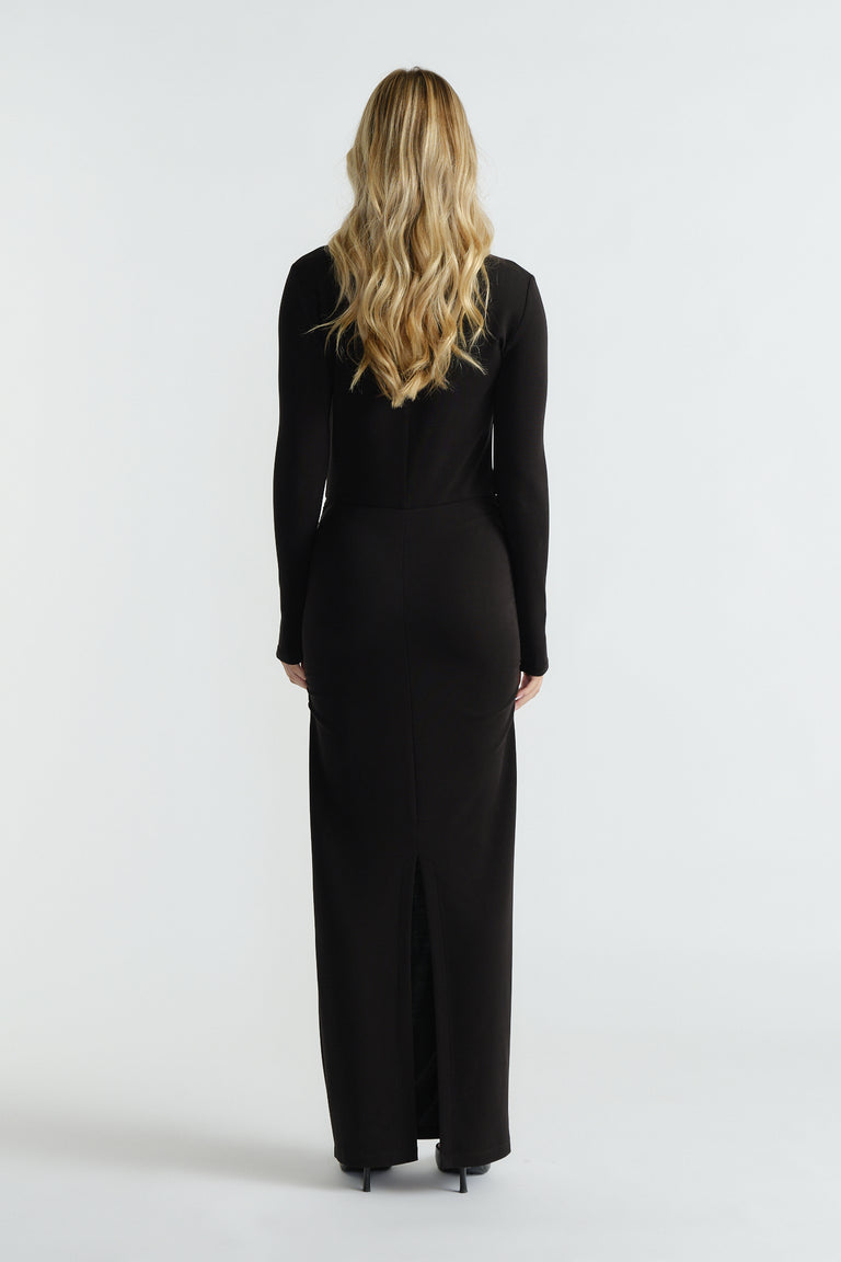Slim-fitting black long-sleeve midi dress with subtle back slit, styled for an elegant and timeless silhouette.