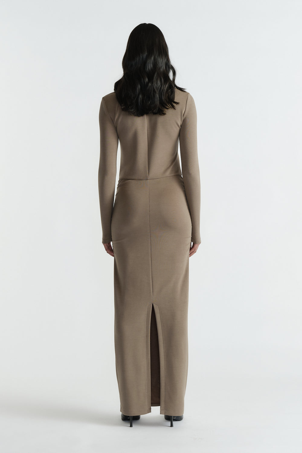 Back view of woman wearing a fitted khaki long-sleeve midi dress with a back slit and clean seam details
