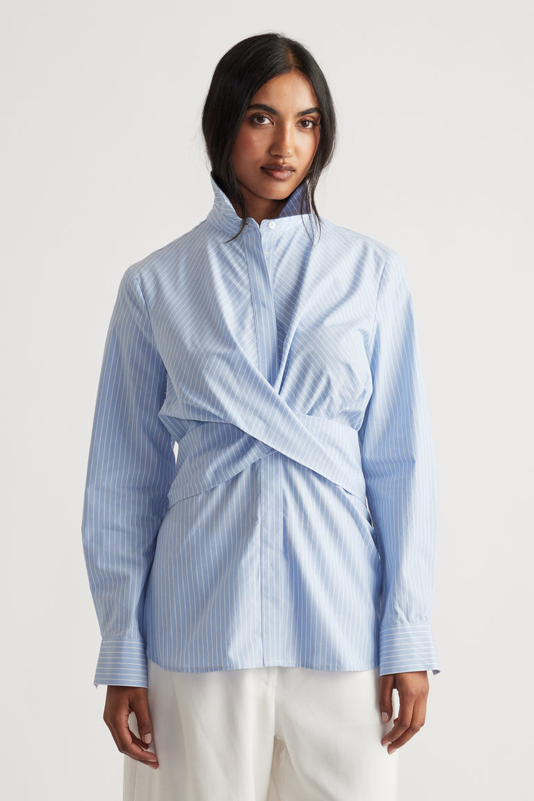 Light blue pinstripe shirt with wrap front detail and structured collar, styled for a modern everyday look