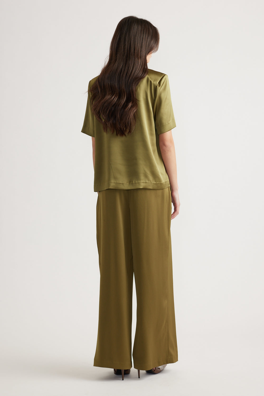 Woman wearing a relaxed fit chartreuse satin top with shoulder pads and matching wide-leg satin pants, viewed from behind