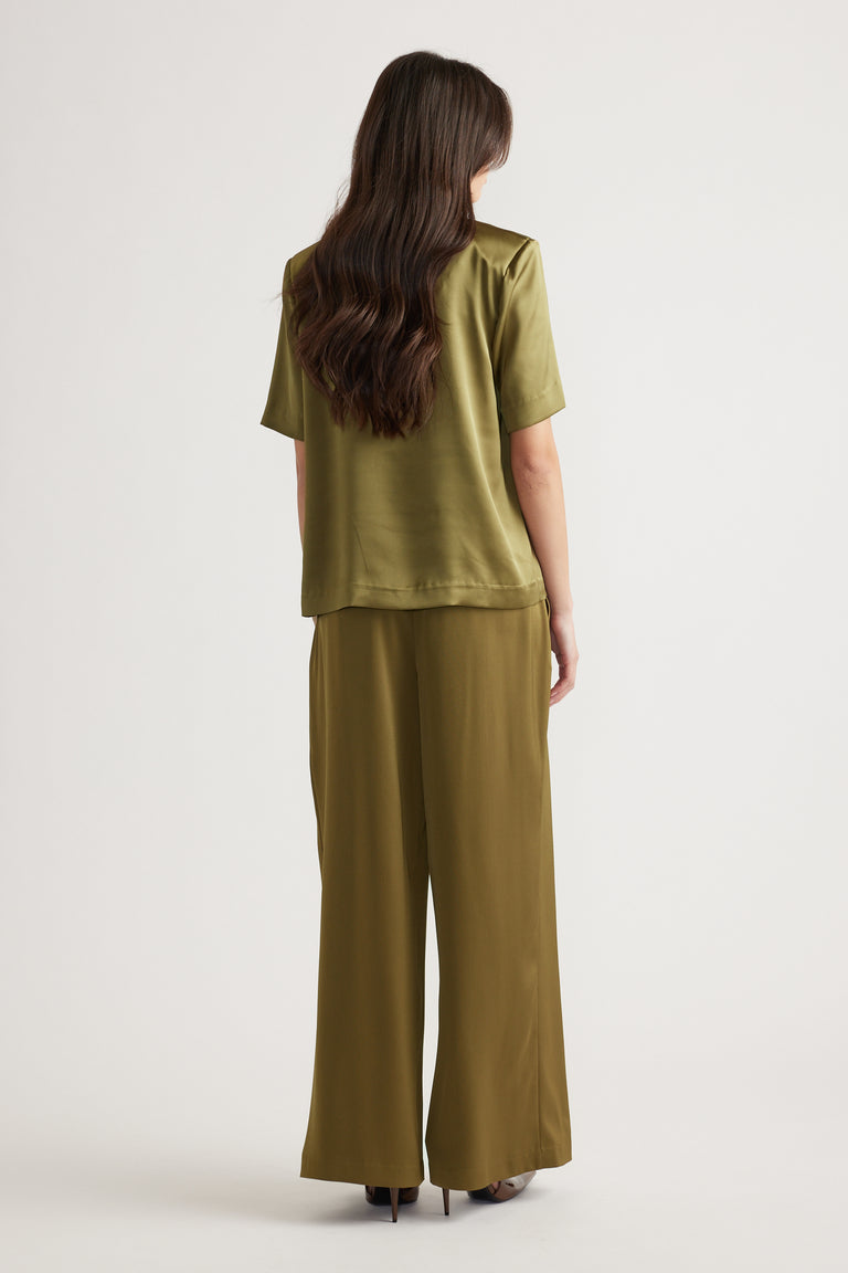 Woman wearing a relaxed fit chartreuse satin top with shoulder pads and matching wide-leg satin pants, viewed from behind