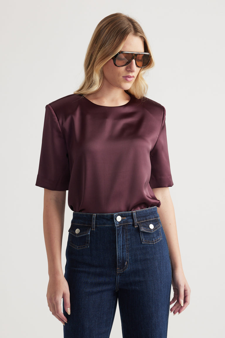 Woman wearing a burgundy satin shoulder pad top with jeans and sunglasses