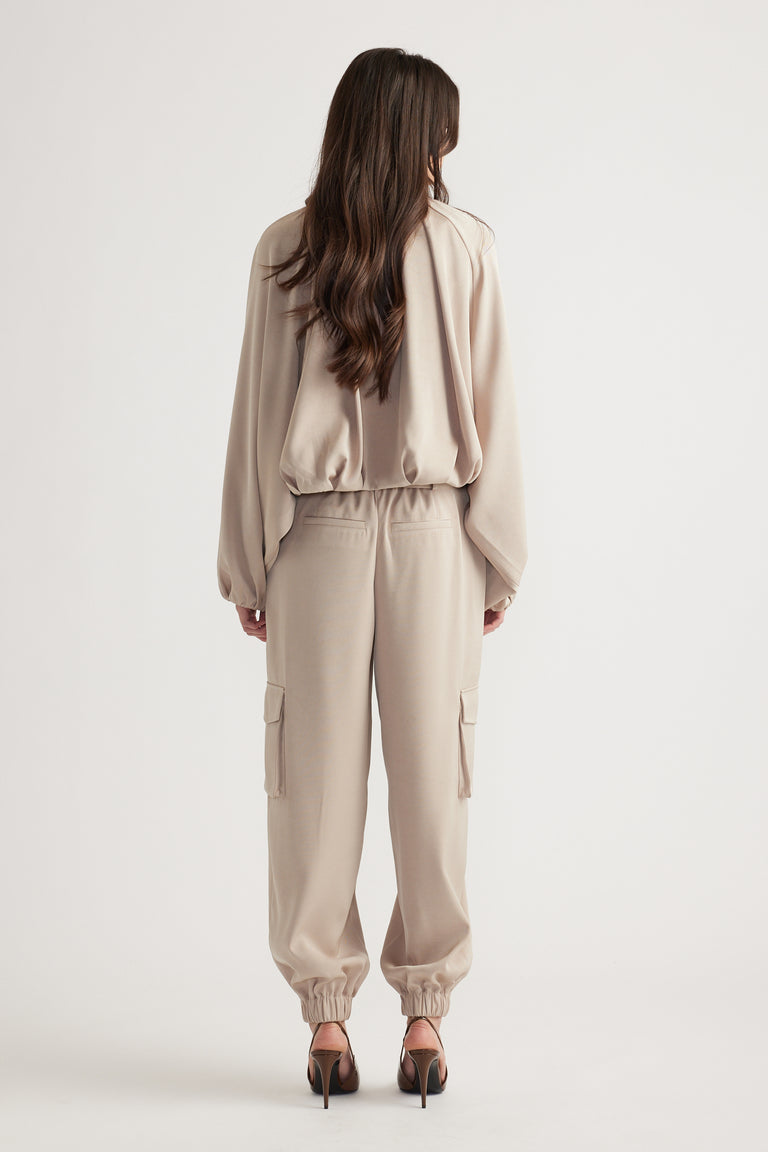 Woman wearing relaxed beige satin cargo pants with cuffed ankles paired with a loose matching top in soft fabric