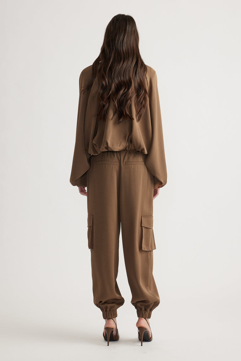 Back view of relaxed fit satin cargo pants in warm bronze with cuffed ankles and flap pockets, styled with matching top