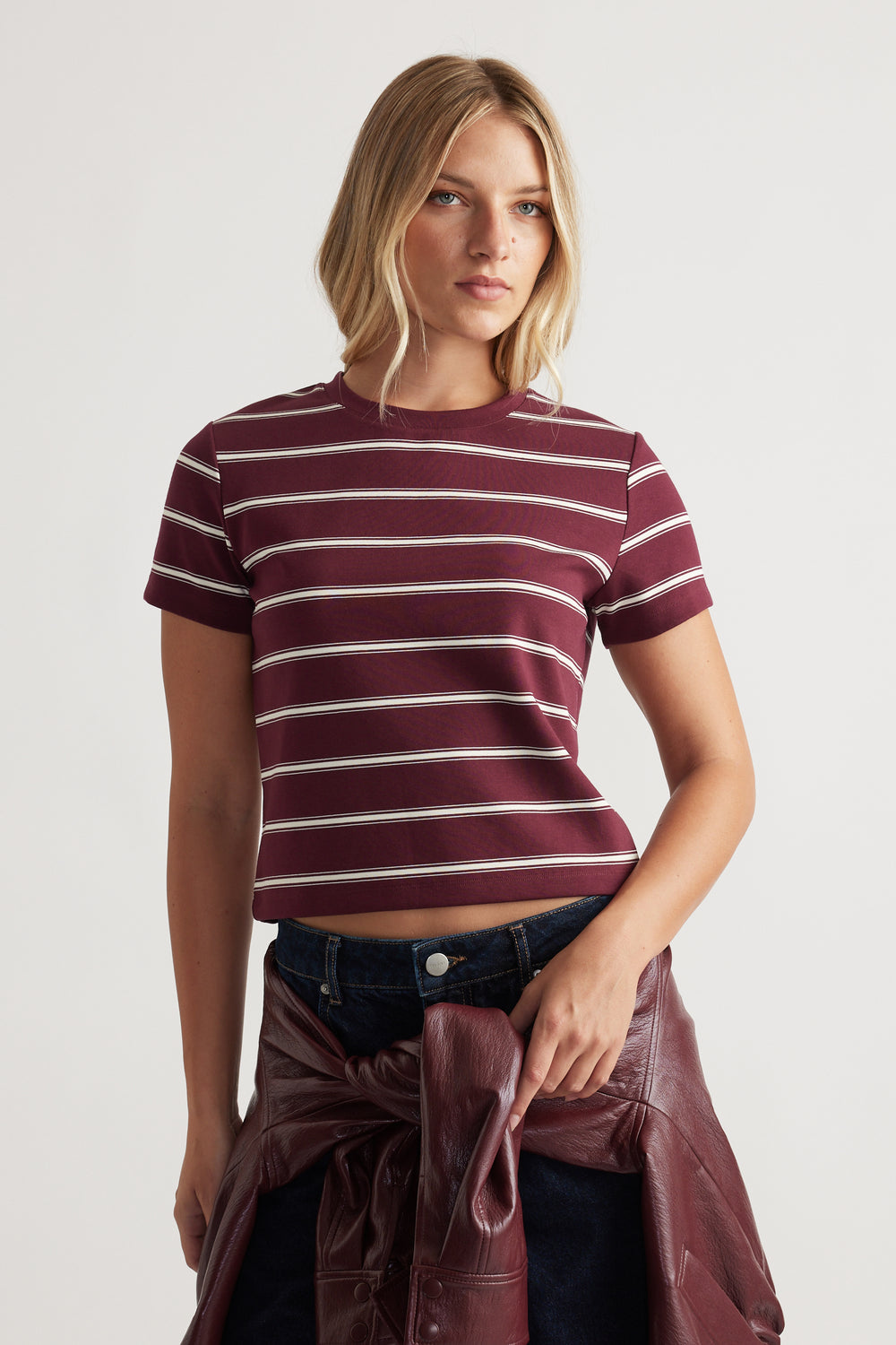 Fitted short sleeve mini tee with horizontal white stripes in a deep plum tone, styled with dark denim and a leather jacket.