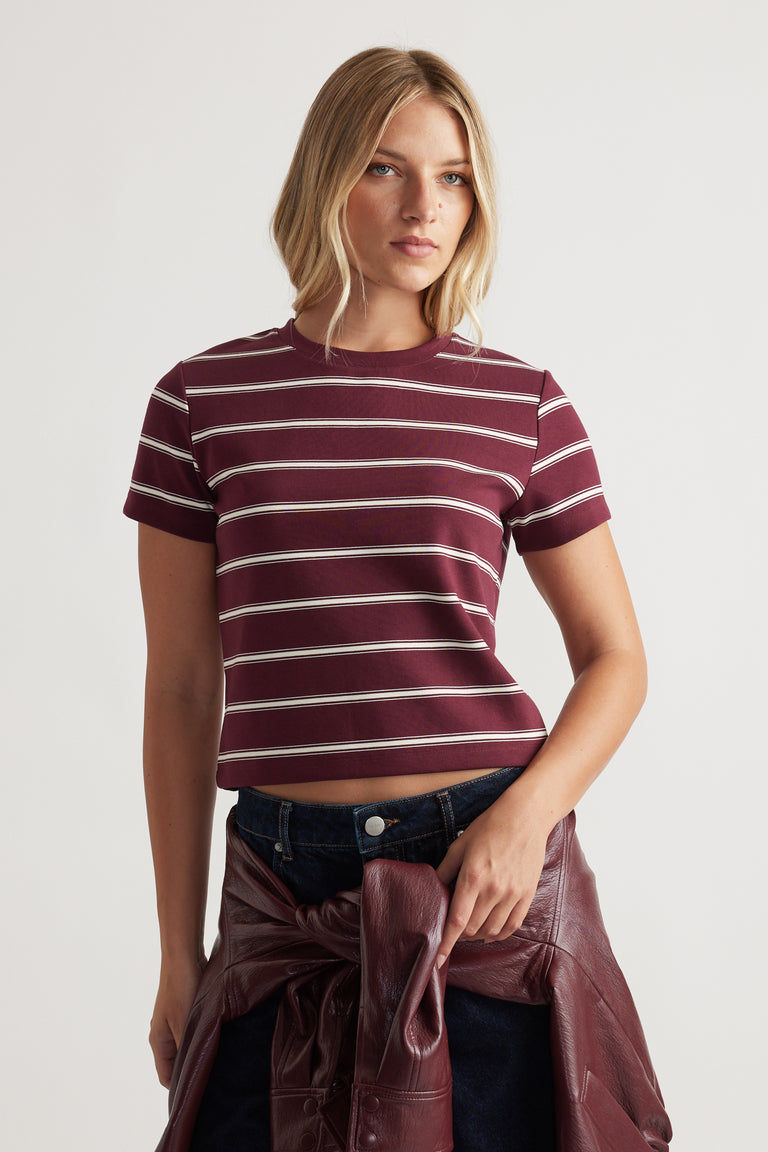 Fitted short sleeve mini tee with horizontal white stripes in a deep plum tone, styled with dark denim and a leather jacket.