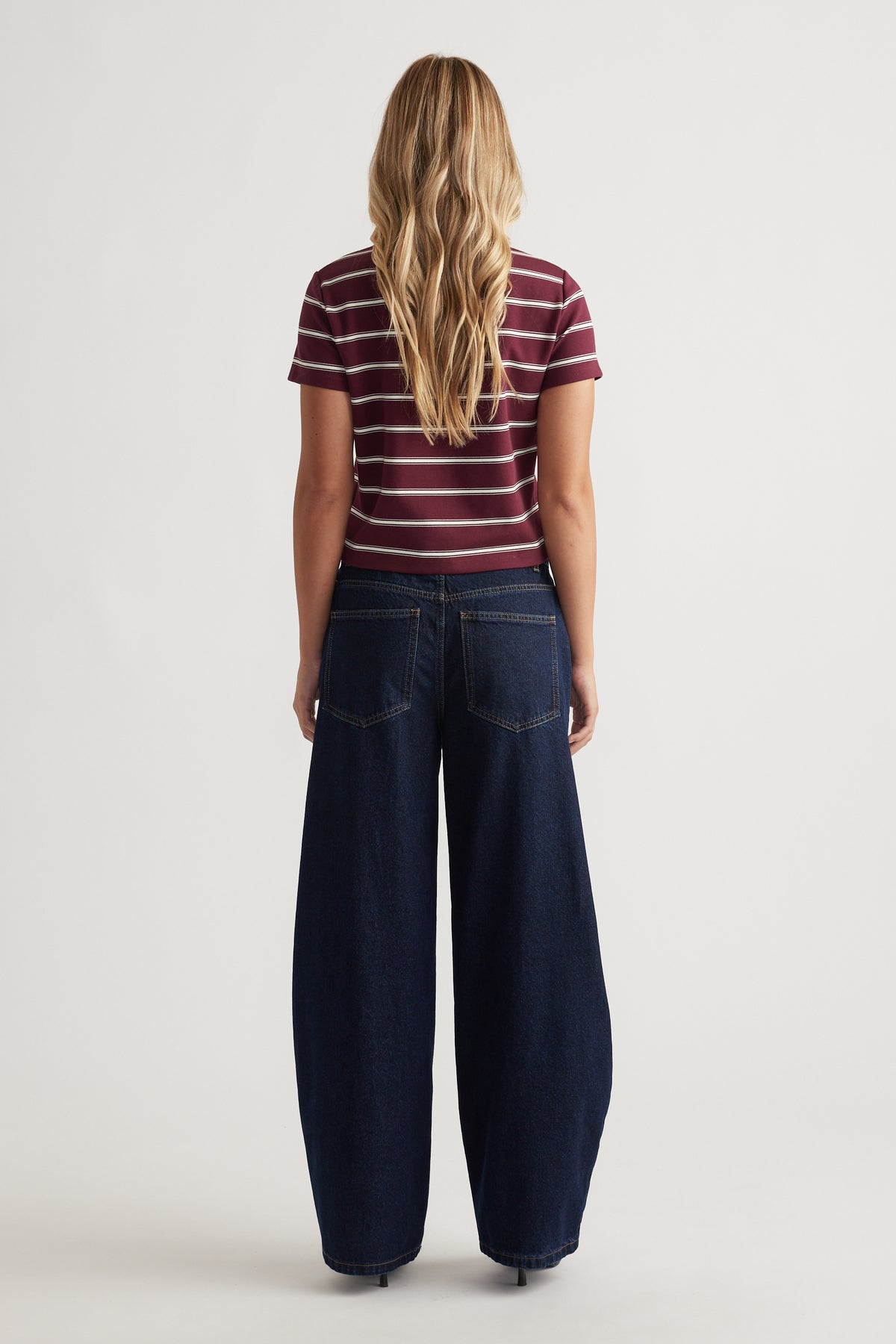 Back view of a plum striped short sleeve tee paired with wide-leg dark denim jeans for a casual look