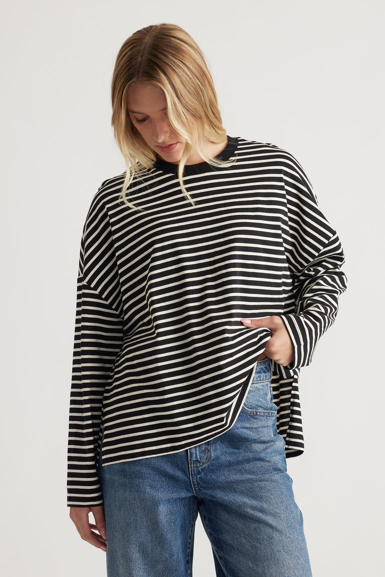 Woman wearing a relaxed black and ivory striped long sleeve top paired with casual blue denim jeans for an easy everyday look