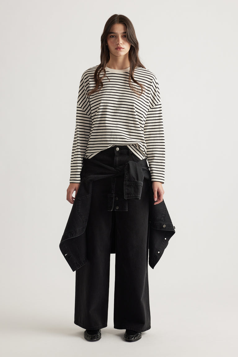 Woman wearing a relaxed striped long sleeve top paired with wide-leg black pants and a black jacket tied at the waist