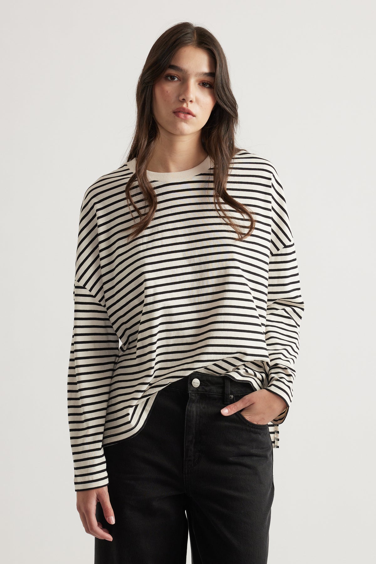 Woman wearing a relaxed striped long sleeve top paired with high-waisted black denim jeans for a casual look