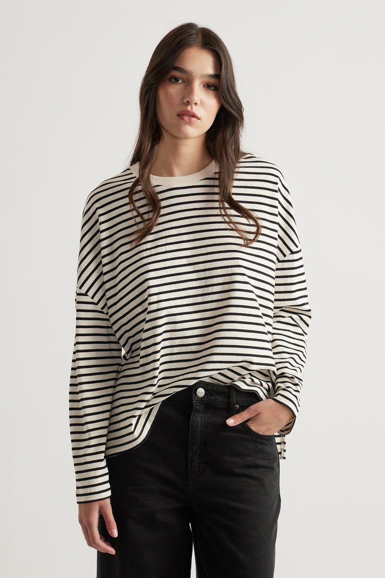 Woman wearing a relaxed striped long sleeve top paired with high-waisted black denim jeans for a casual look