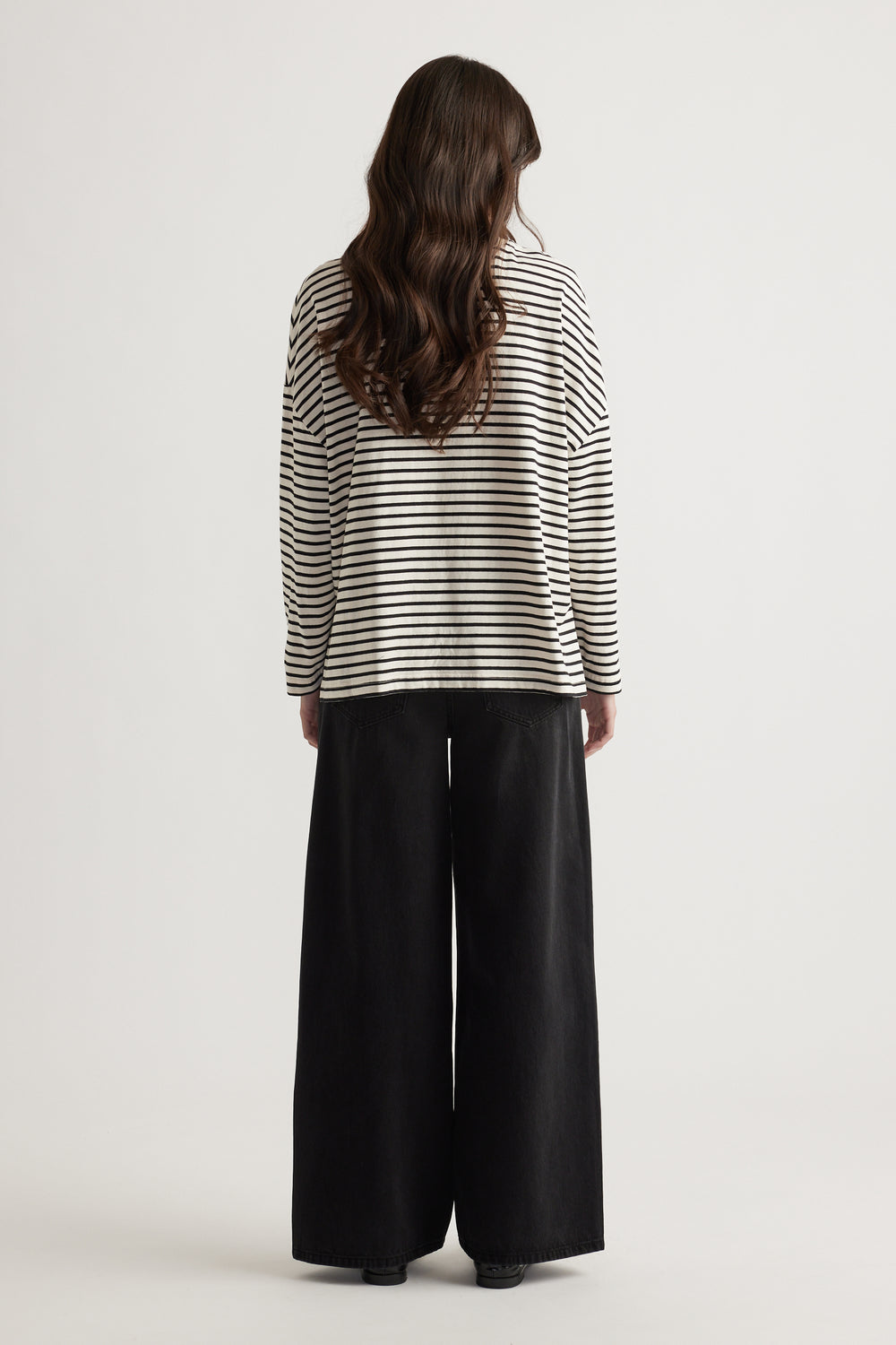 Woman seen from behind wearing a relaxed striped long sleeve top paired with wide-leg black pants for a casual look