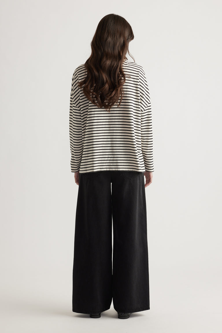 Woman seen from behind wearing a relaxed striped long sleeve top paired with wide-leg black pants for a casual look