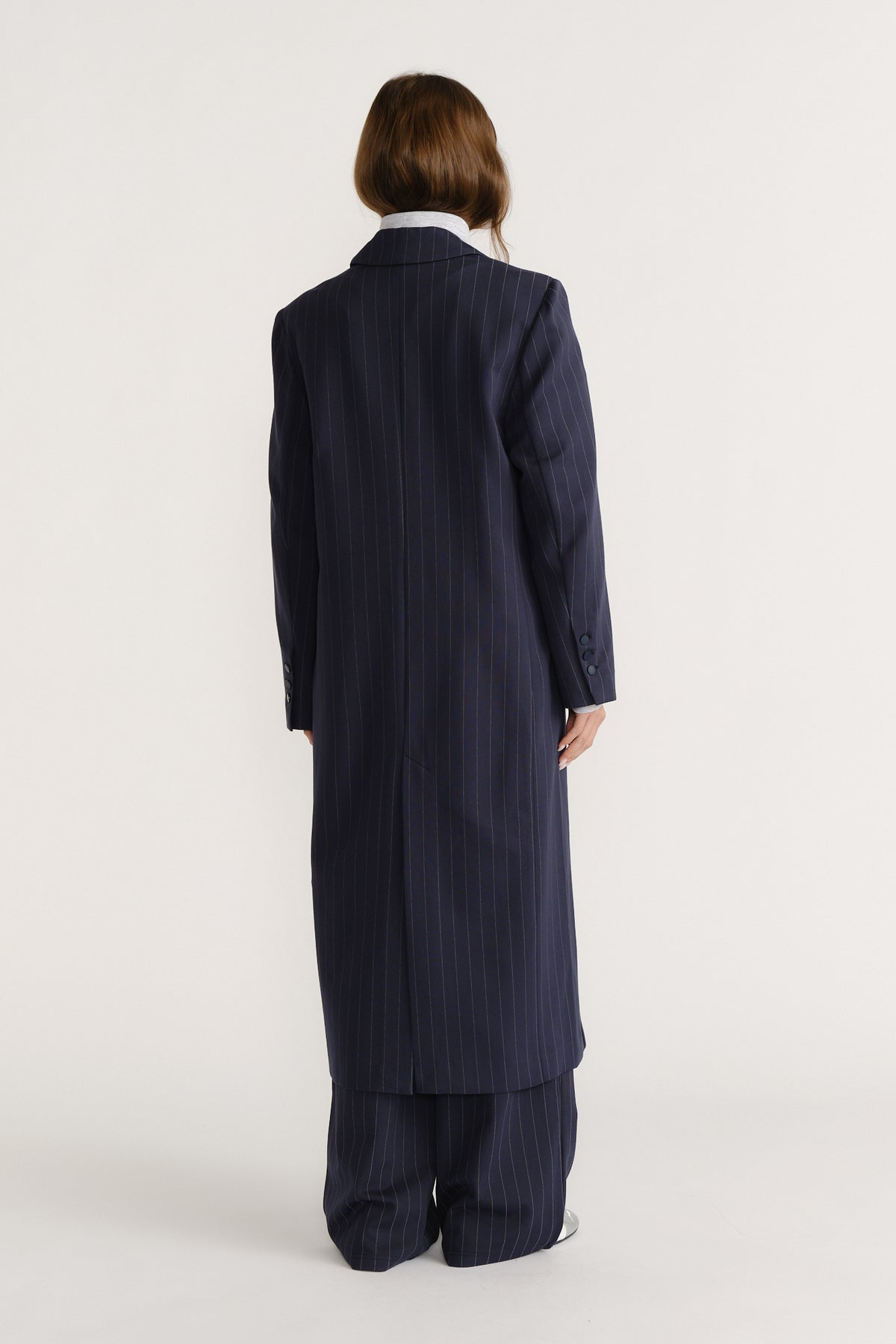 Woman seen from behind wearing a navy long pinstripe blazer coat with matching wide-leg pants for a polished look