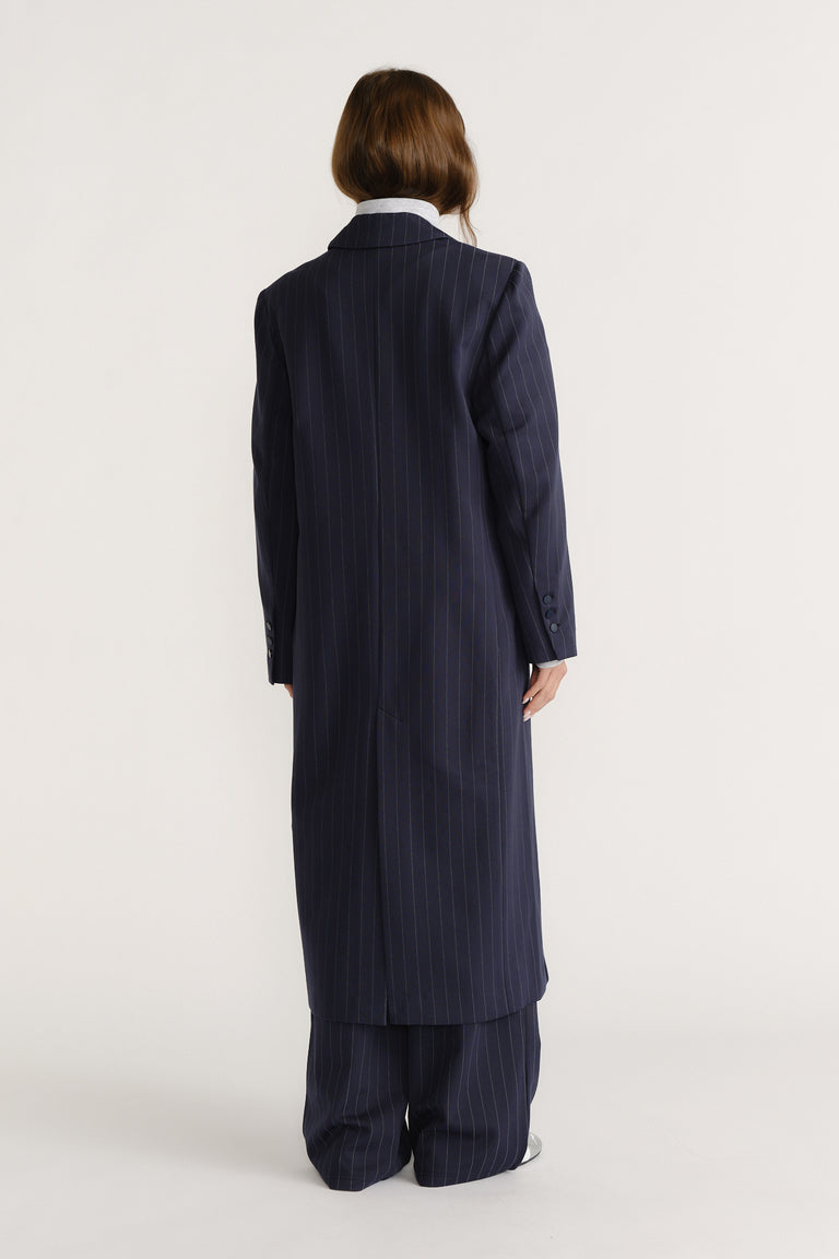 Woman seen from behind wearing a navy long pinstripe blazer coat with matching wide-leg pants for a polished look