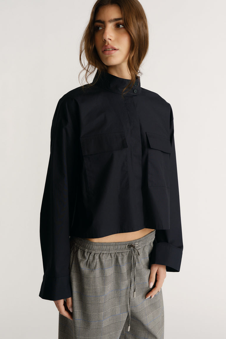 Woman wearing a cropped navy utility shirt with oversized cuffs paired with drawstring checked pants