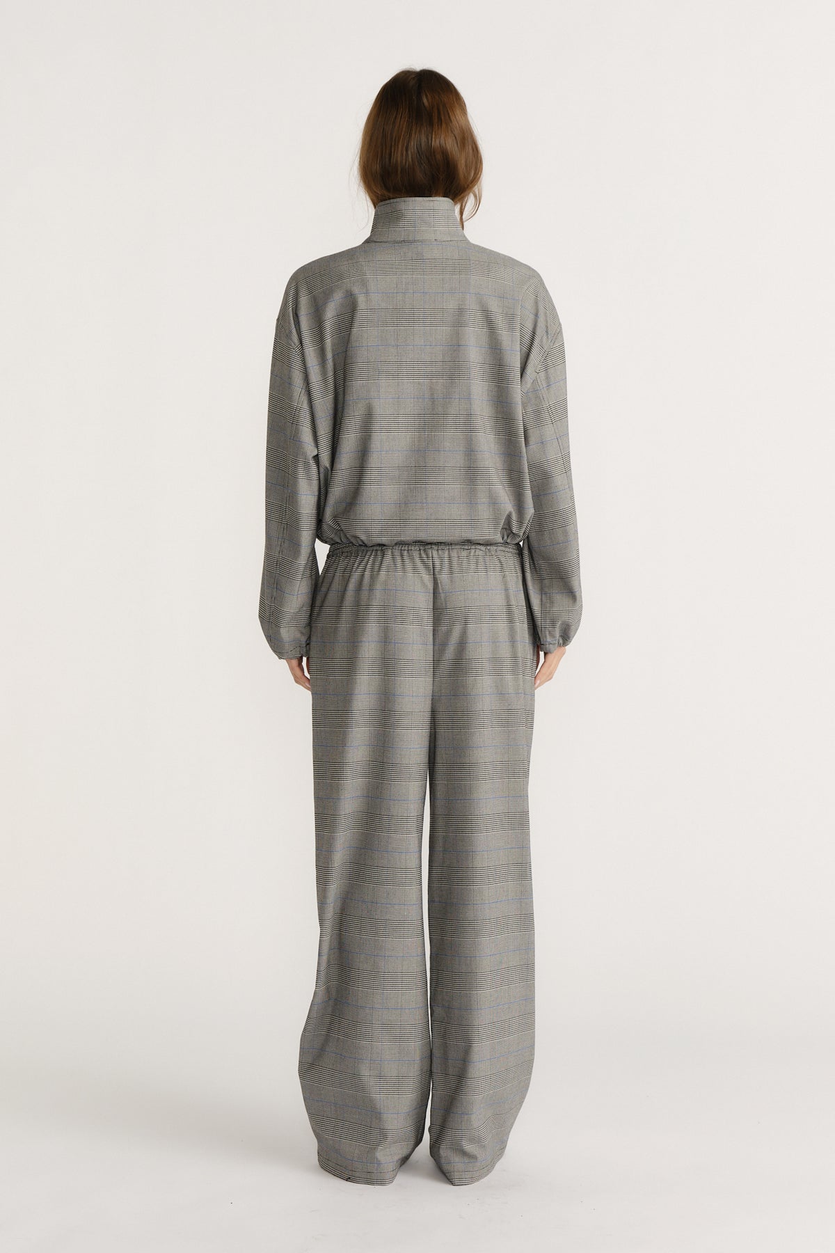 Back view of a relaxed-fit grey checked jacket and matching wide-leg pants set against a neutral background.