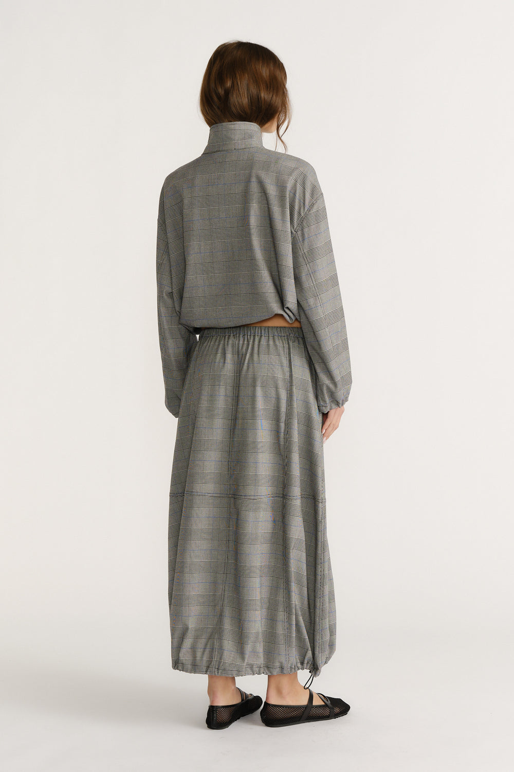 Back view of woman wearing relaxed fit check cocoon skirt with elastic waist and matching long-sleeve top