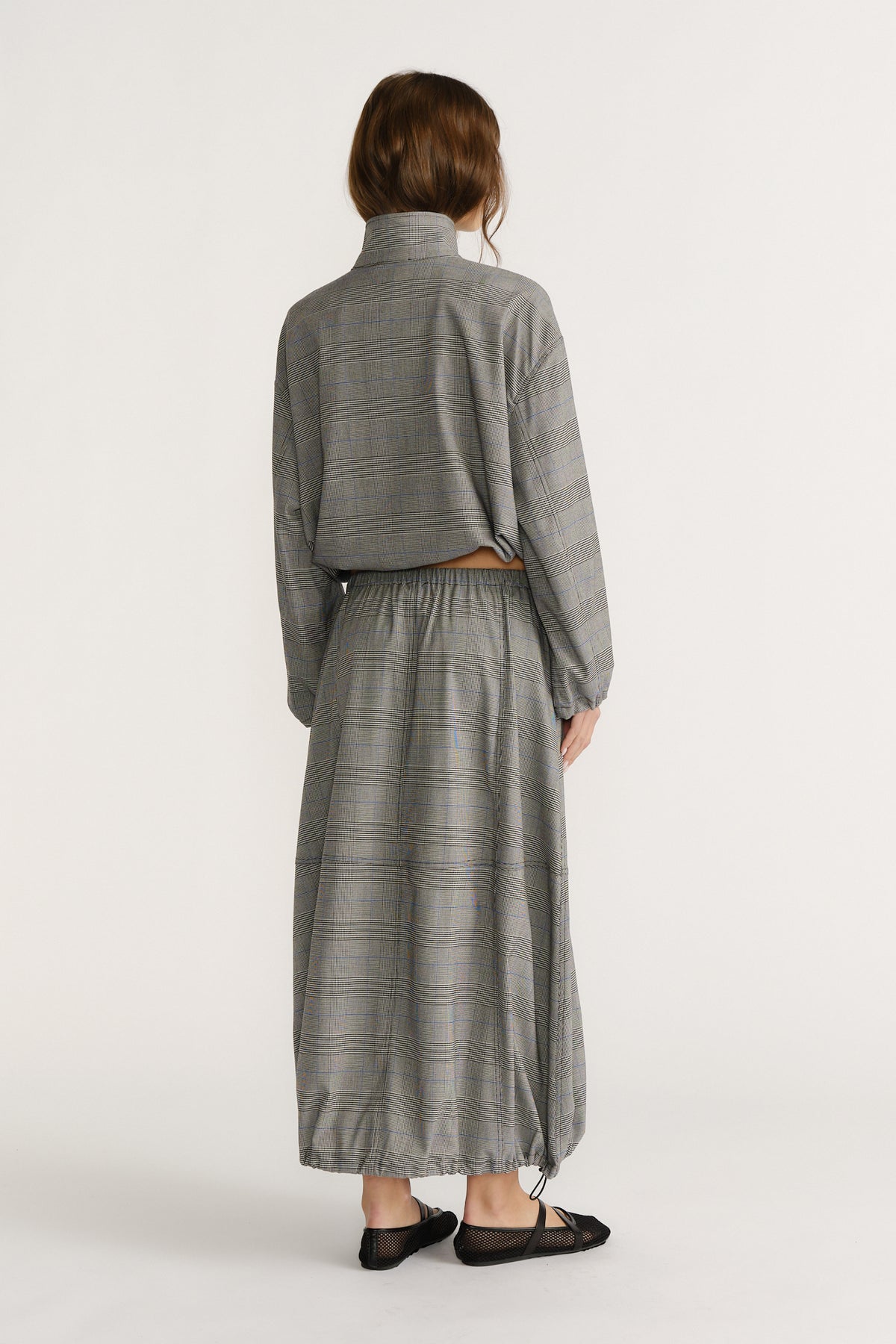 Back view of woman wearing relaxed fit check cocoon skirt with elastic waist and matching long-sleeve top