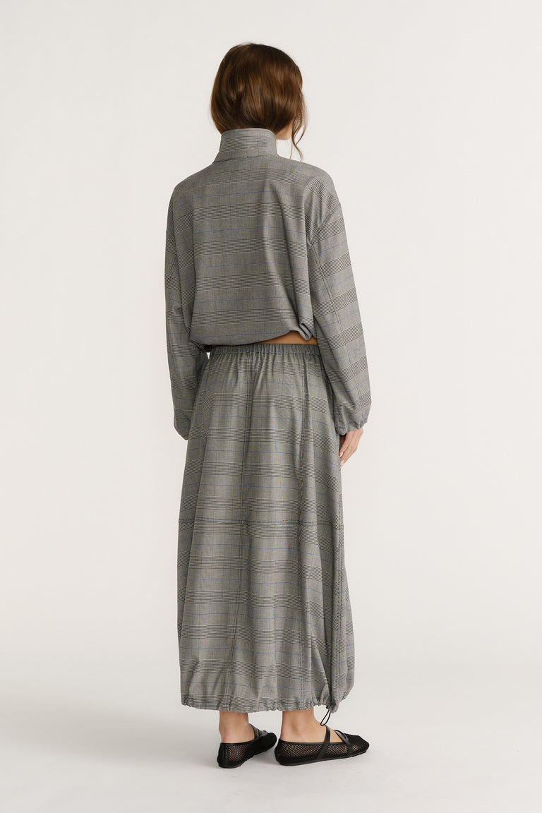 Back view of woman wearing relaxed fit check cocoon skirt with elastic waist and matching long-sleeve top