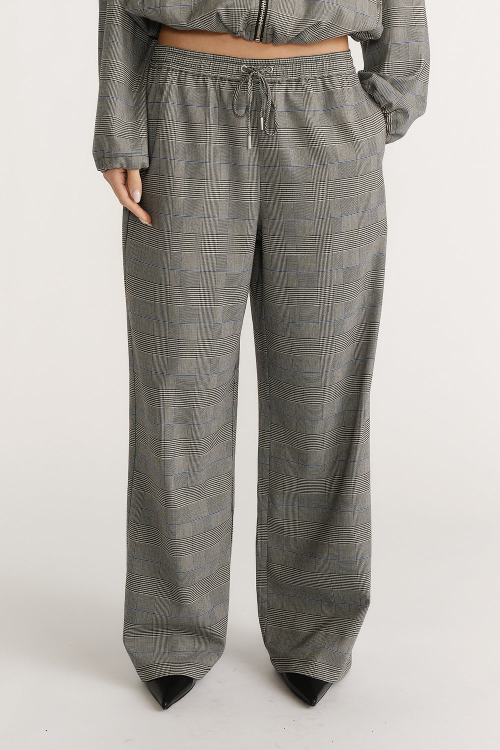 Relaxed fit check pants with a drawstring waist paired with black pointed-toe shoes for a polished look.