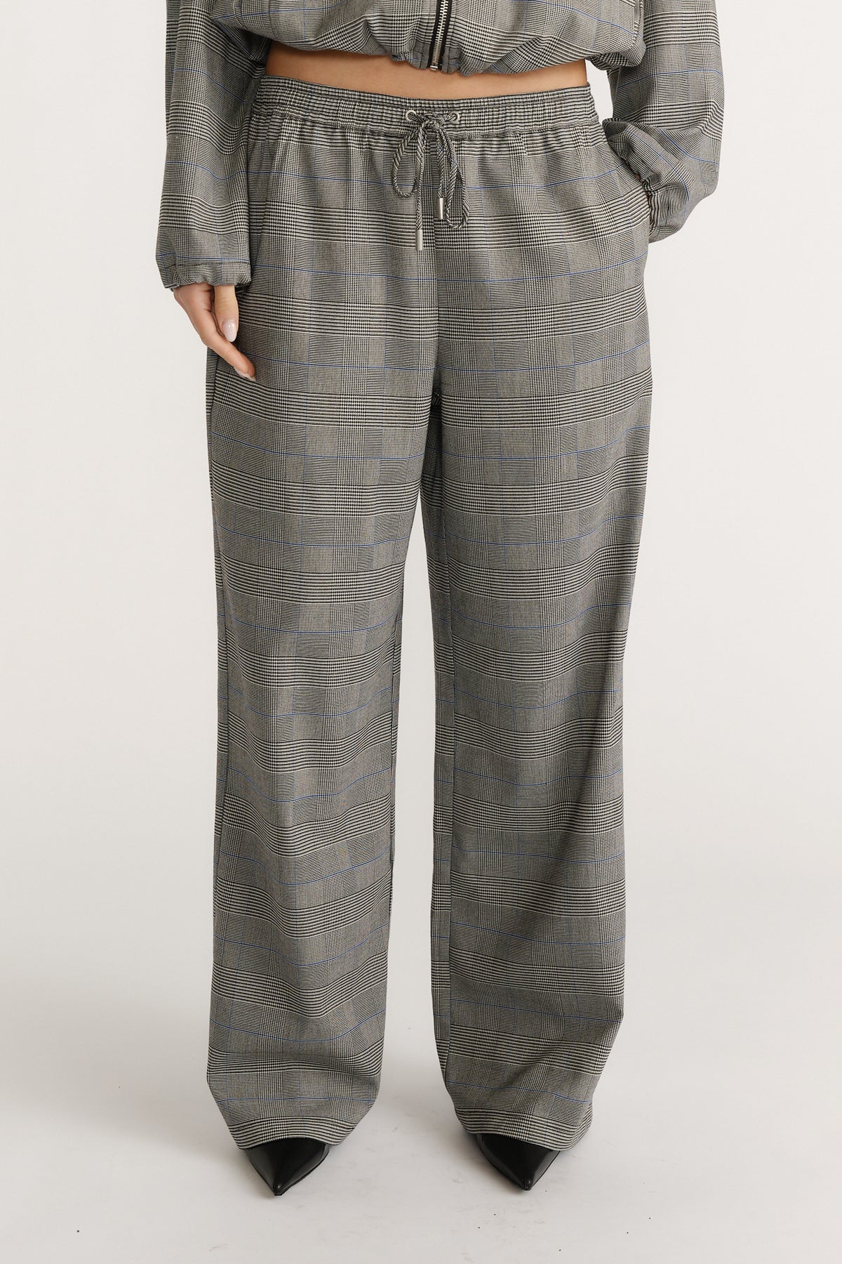 Relaxed fit check pants with a drawstring waist paired with black pointed-toe shoes for a polished look.