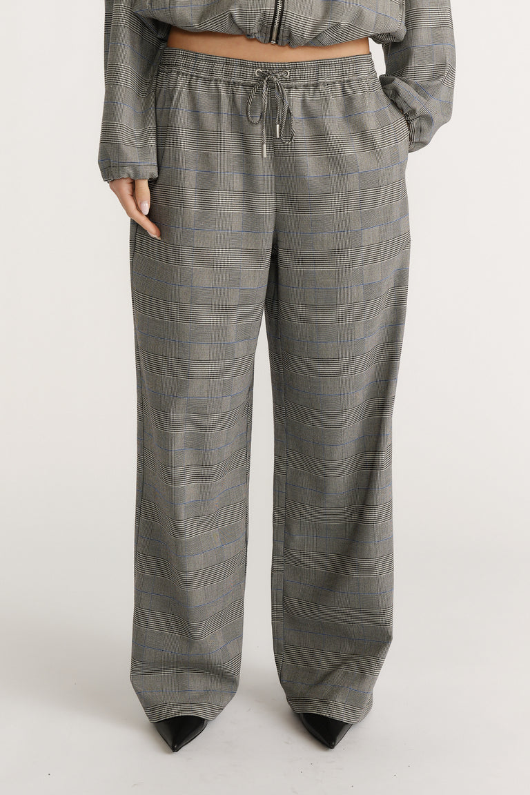 Relaxed fit check pants with a drawstring waist paired with black pointed-toe shoes for a polished look.
