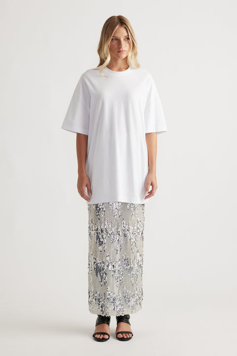 Woman wearing an oversized white tee paired with a silver sequin maxi skirt and black open-toe heels