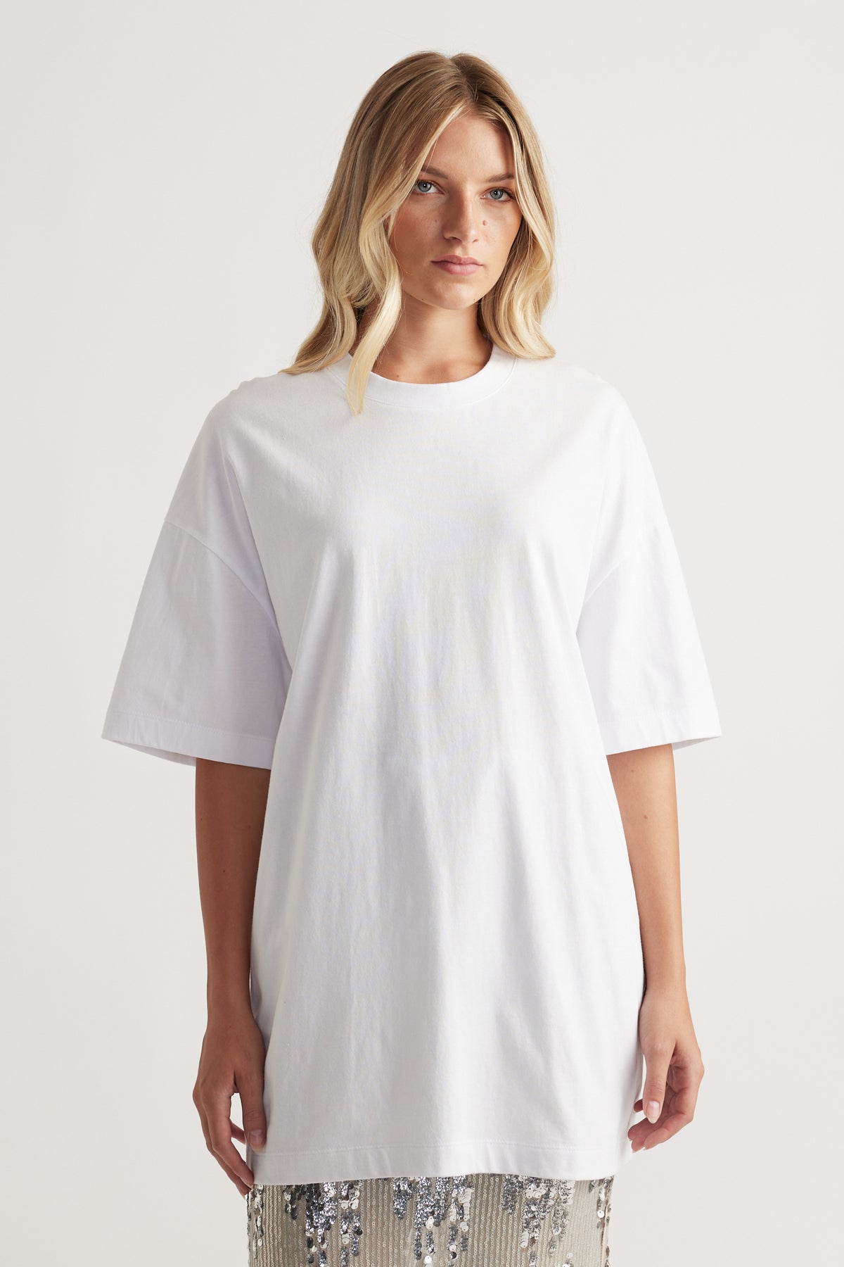 Woman wearing an oversized bright white longline tee with relaxed sleeves for a modern casual style