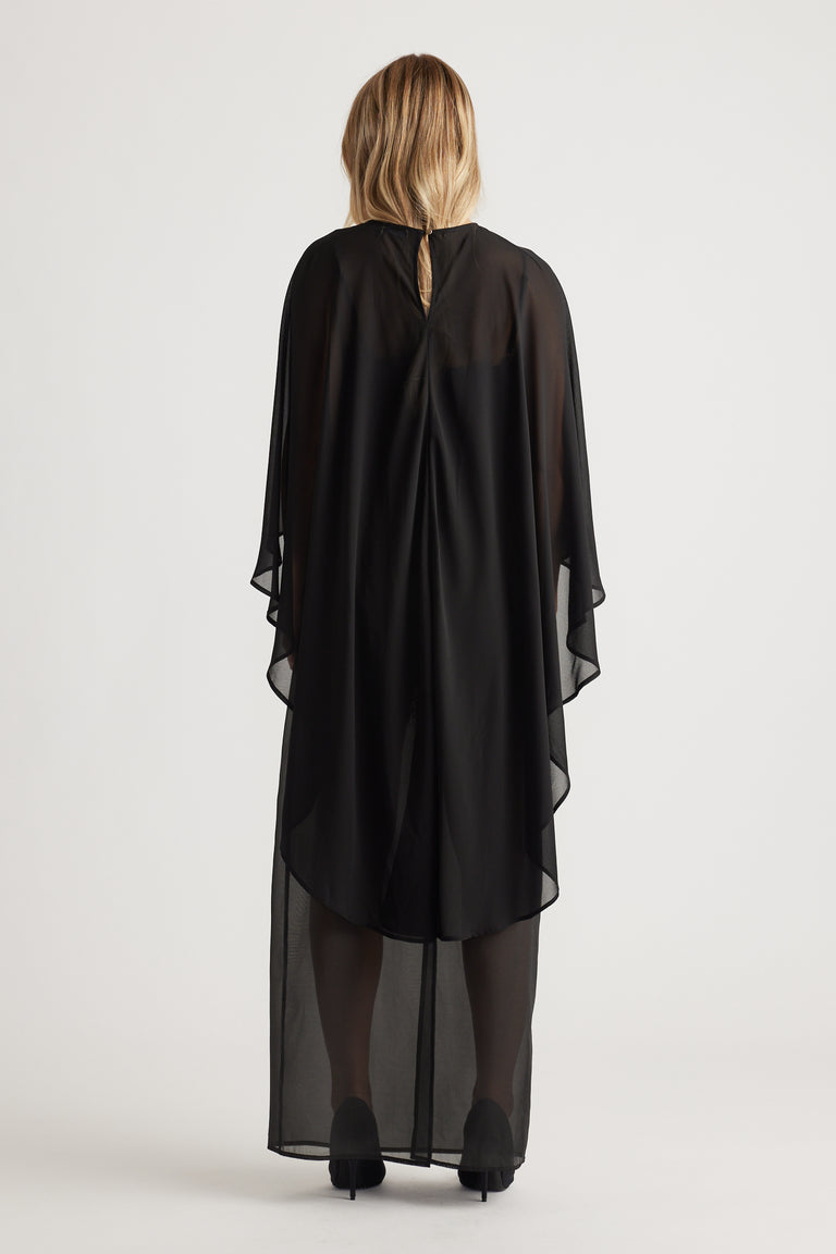 Back view of a flowing black georgette cape top with sheer fabric and a keyhole closure at the neckline