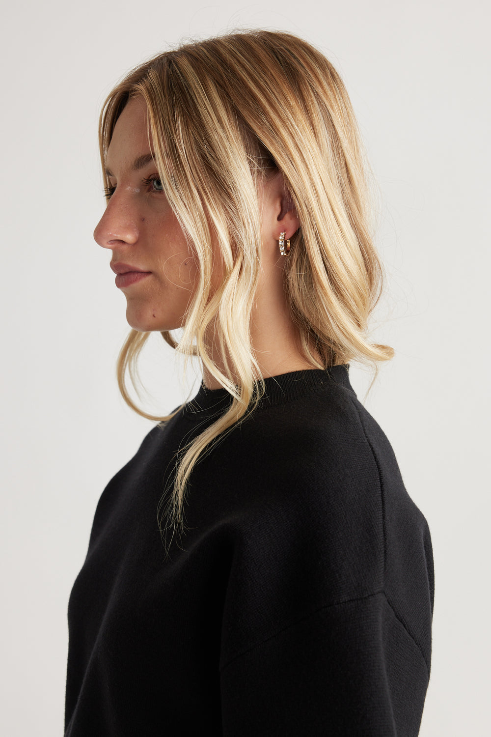 Side profile of a woman wearing gold hoop Cat Earring Multi Pack with textured detail, styled with loose blonde waves
