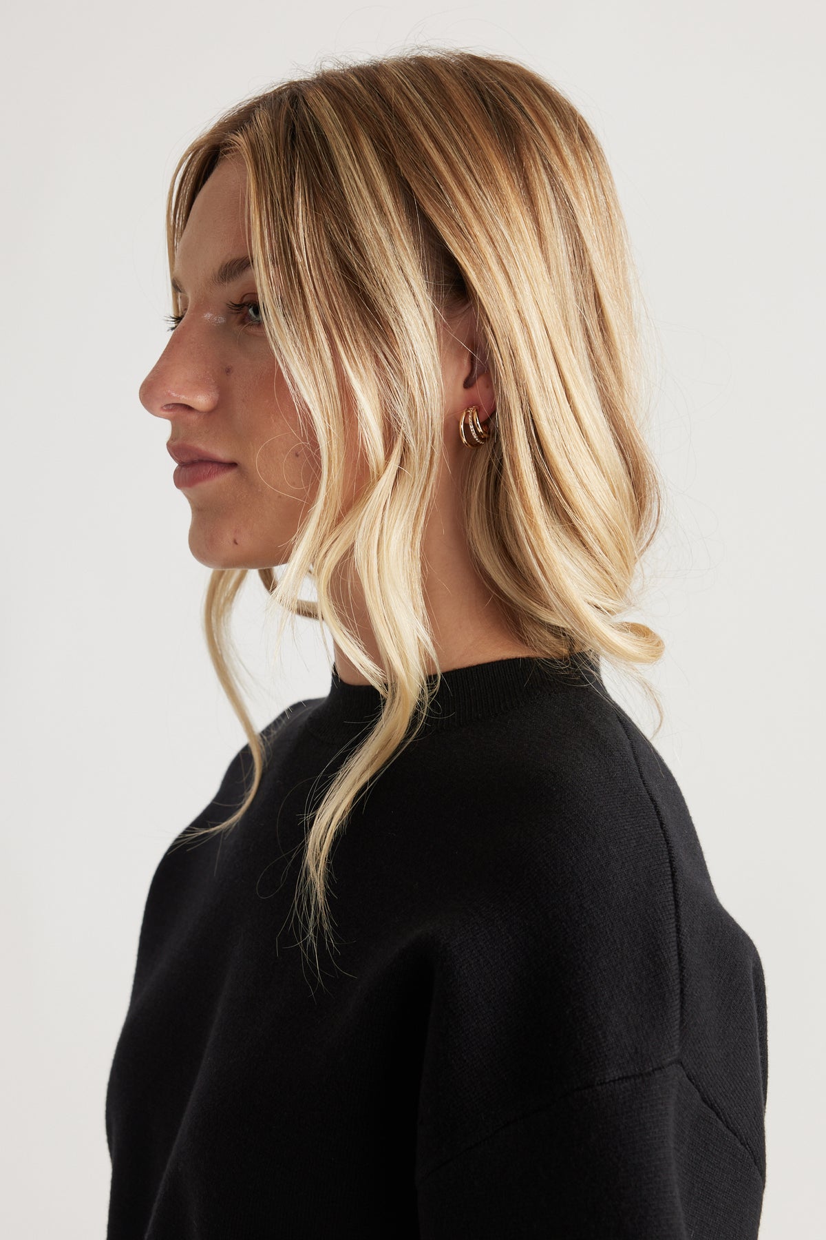 Woman wearing Cat Earring Multi Pack with layered gold-tone hoops, styled with loose waves and a black crew neck top.