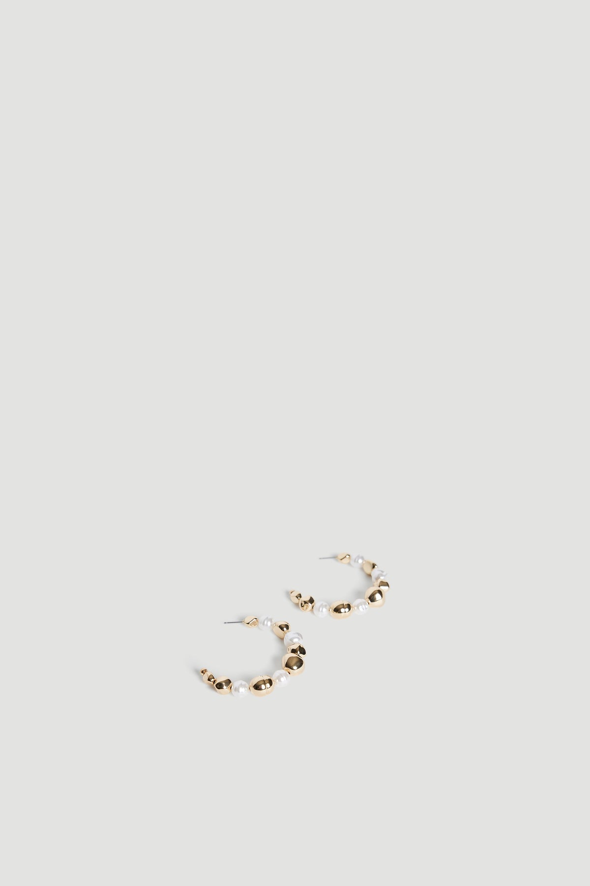 Pair of gold-tone hoop earrings with an organic molten texture and small pearl accents on a neutral background