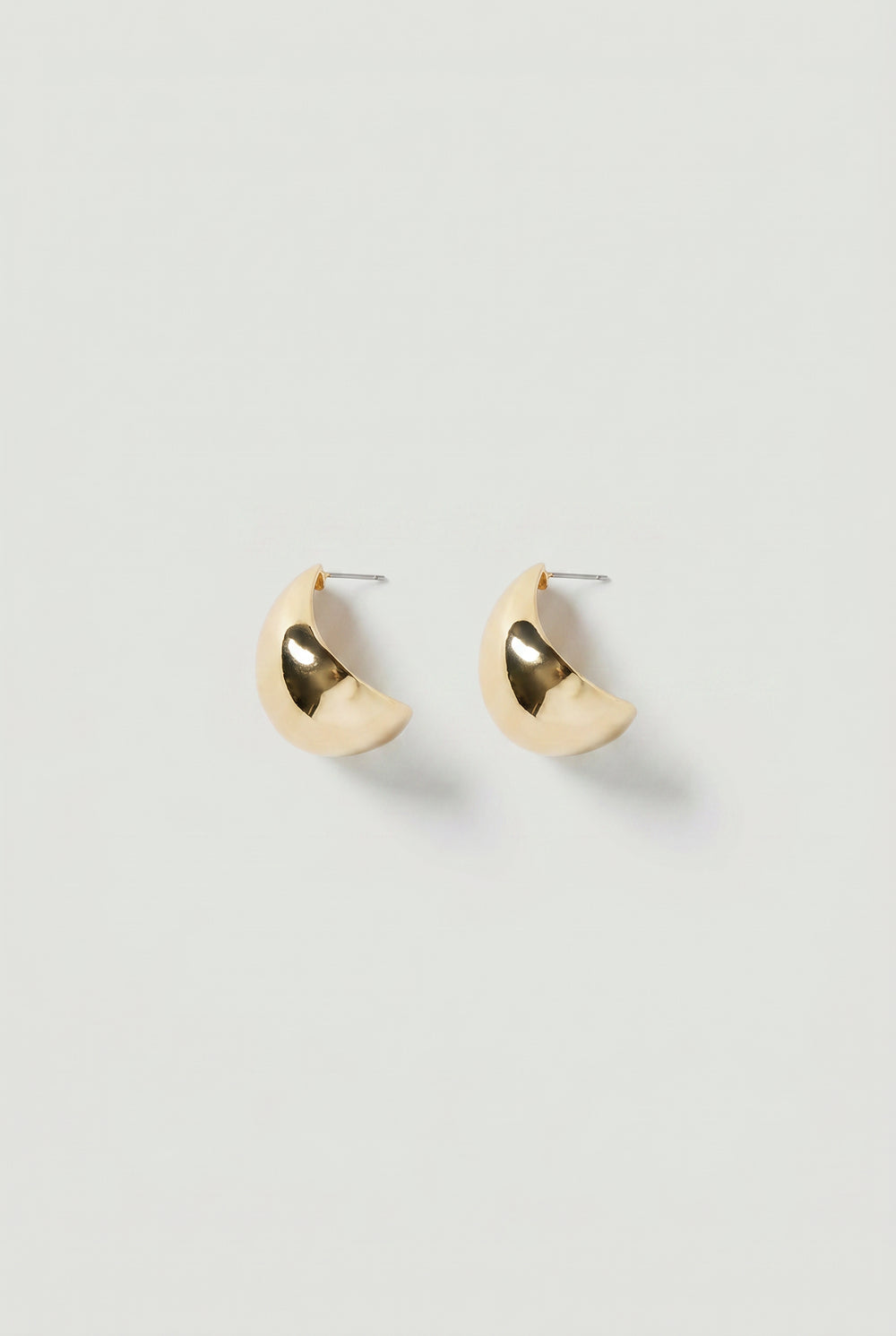 Pair of gold-toned crescent-shaped statement hoop earrings with a polished, reflective finish.
