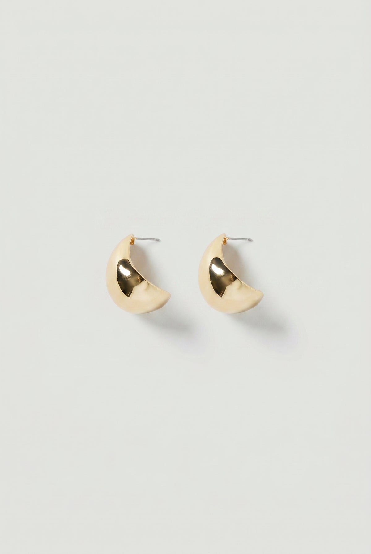 Pair of gold-toned crescent-shaped statement hoop earrings with a polished, reflective finish.