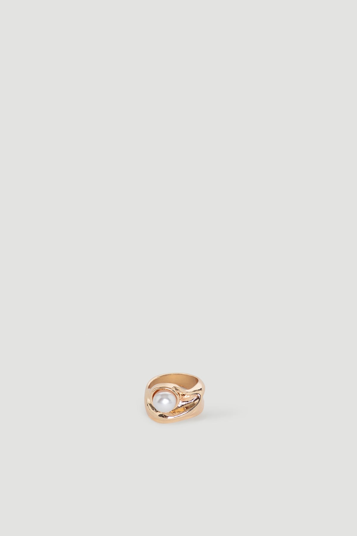 Gold statement ring featuring a smooth pearl centerpiece with an artistic, modern design detail
