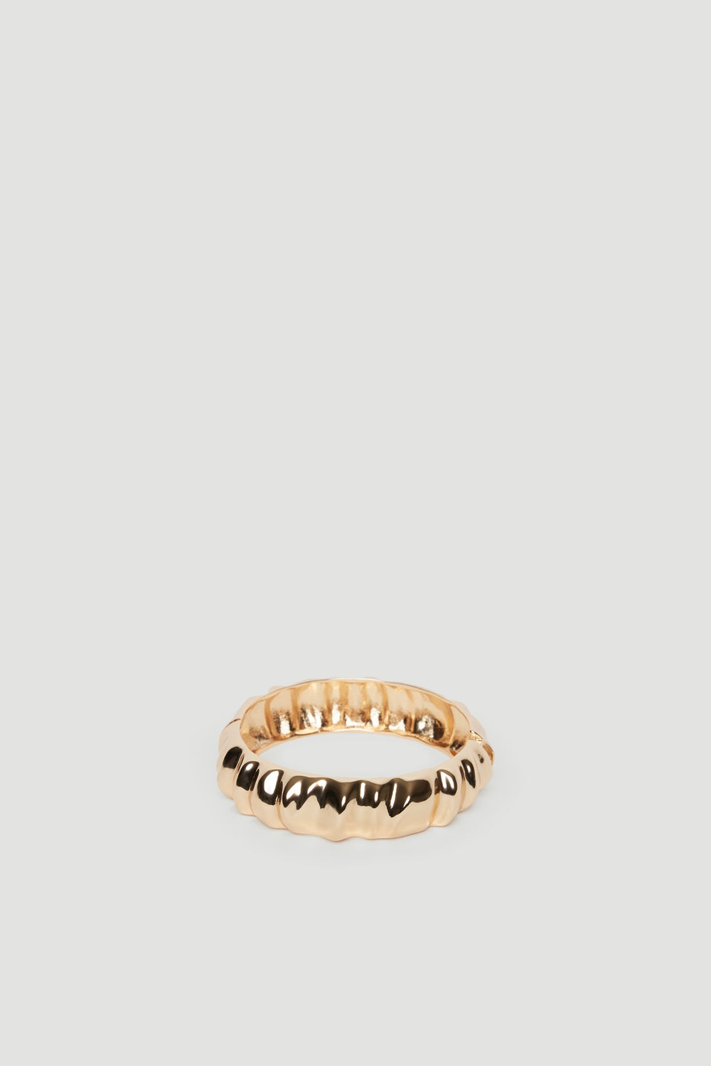 Textured gold cuff bracelet with a polished finish, reflecting a sleek and modern aesthetic.