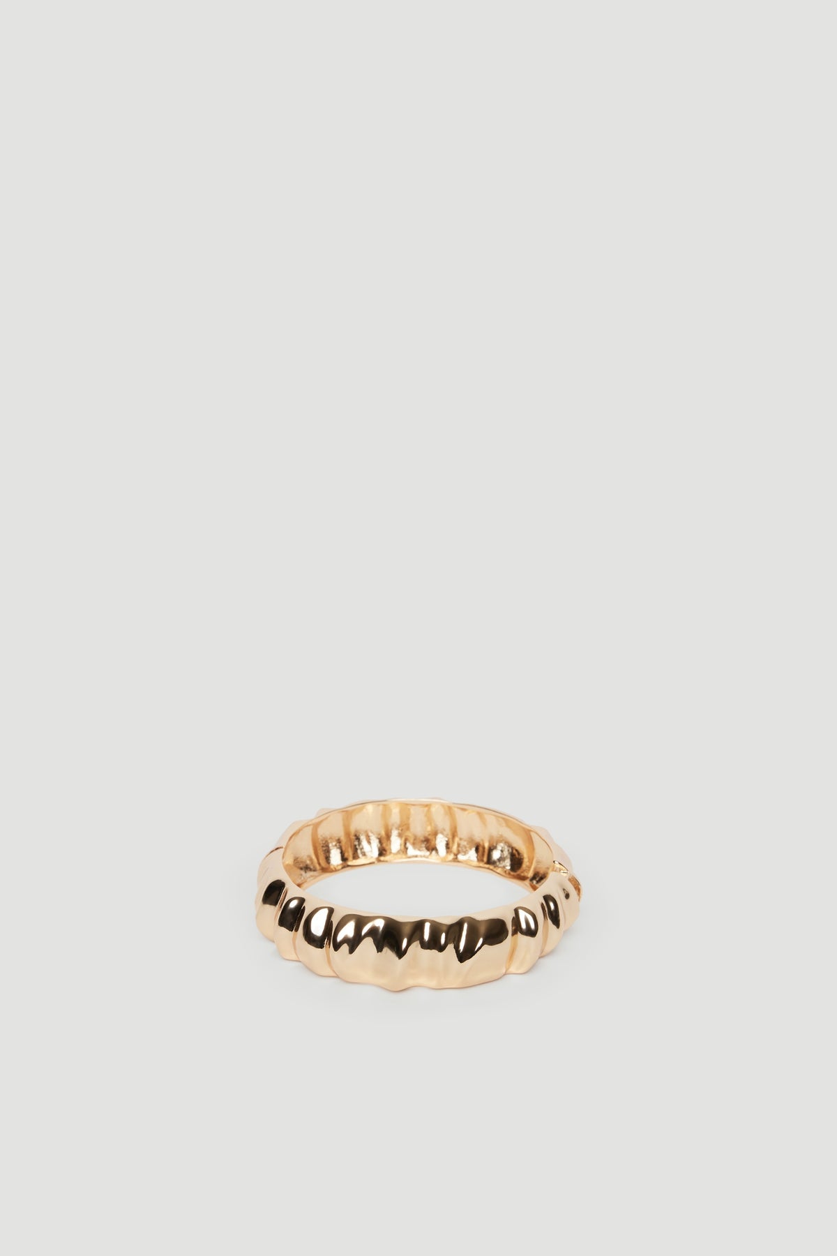 Textured gold cuff bracelet with a polished finish, reflecting a sleek and modern aesthetic.