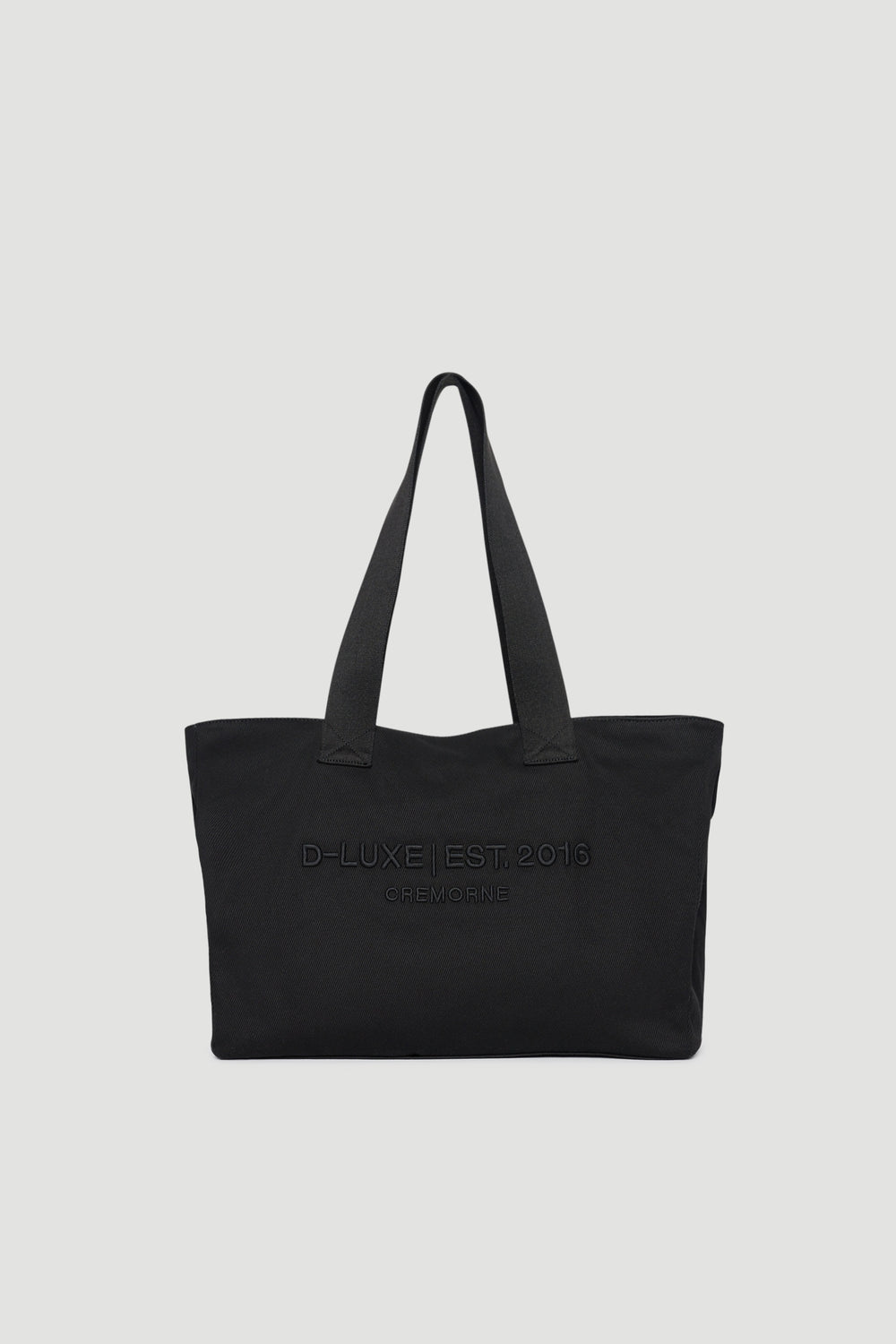 Black structured tote bag with wide shoulder straps and subtle embossed front logo detail
