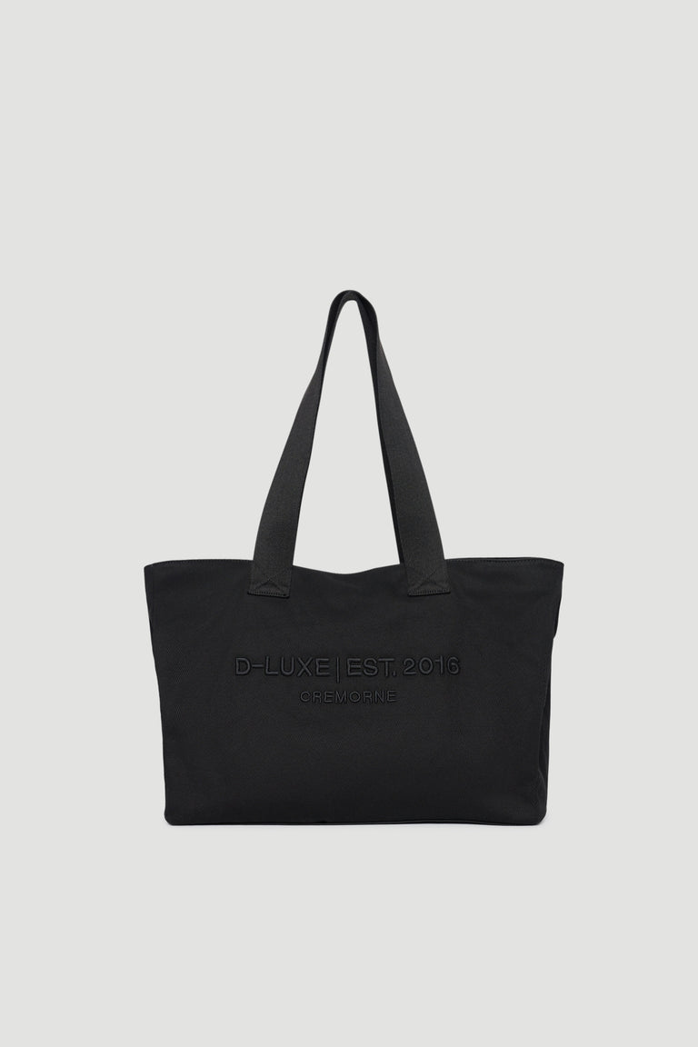 Black structured tote bag with wide shoulder straps and subtle embossed front logo detail