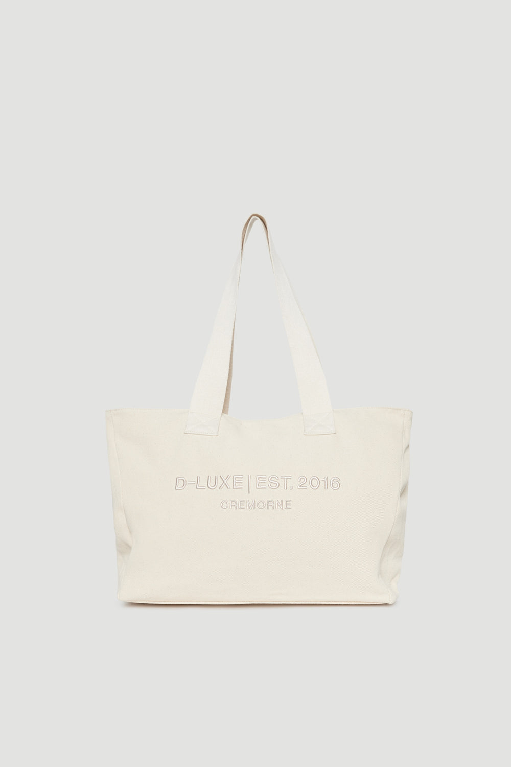 Structured cream tote bag with wide shoulder straps and subtle front logo embroidery detail