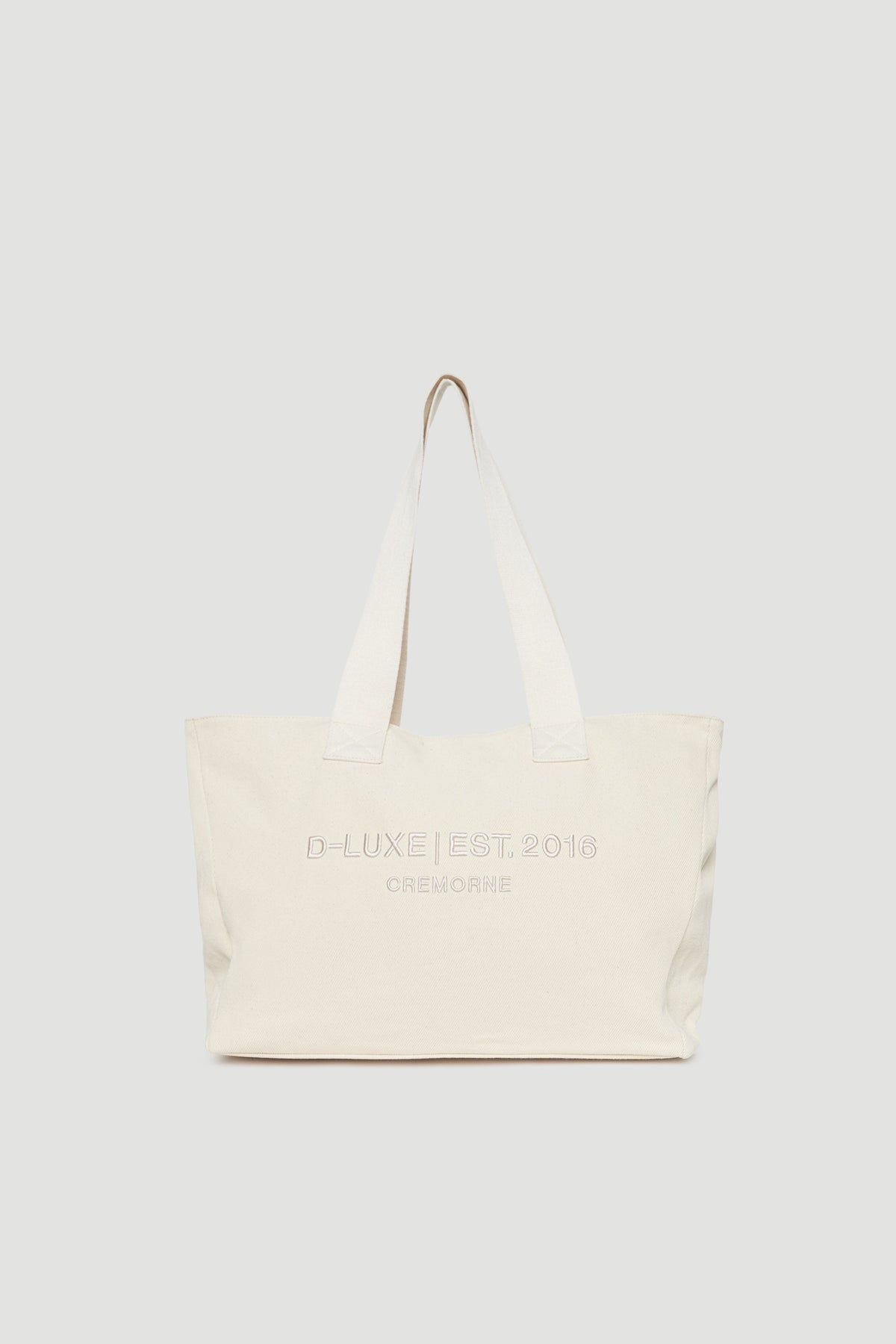 Structured cream tote bag with wide shoulder straps and subtle front logo embroidery detail